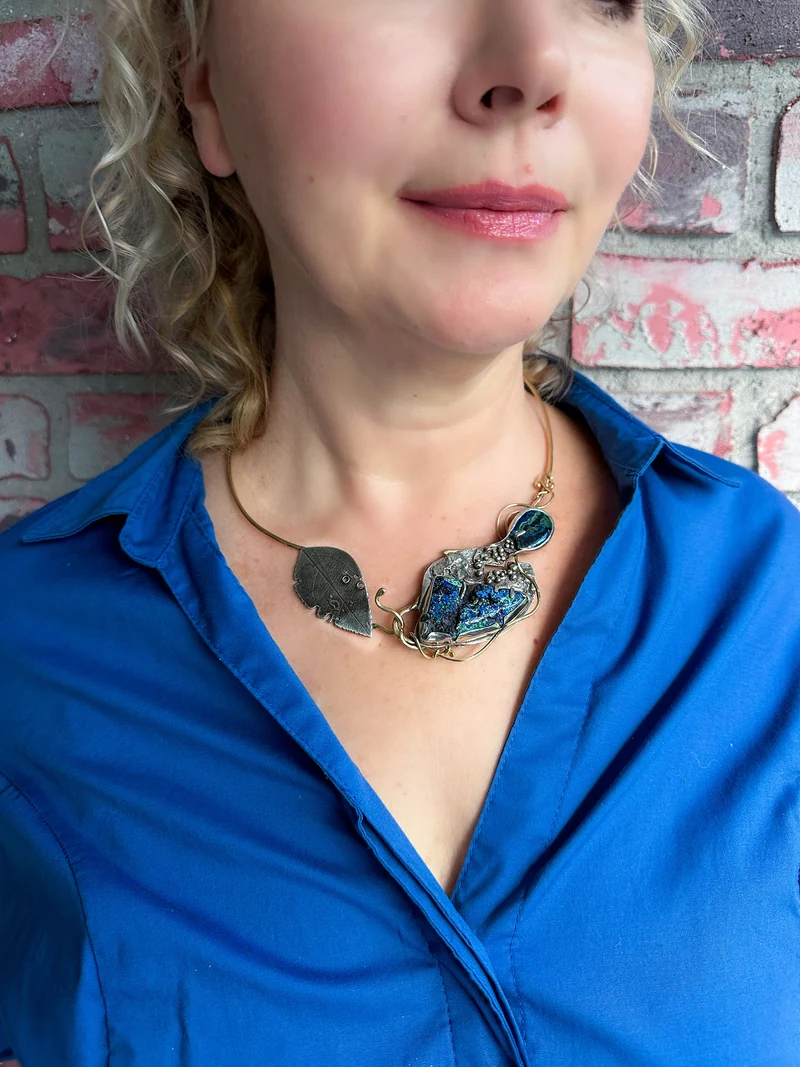 Beyond worn against a blue shirt, showing how the necklace rests on the neckline.